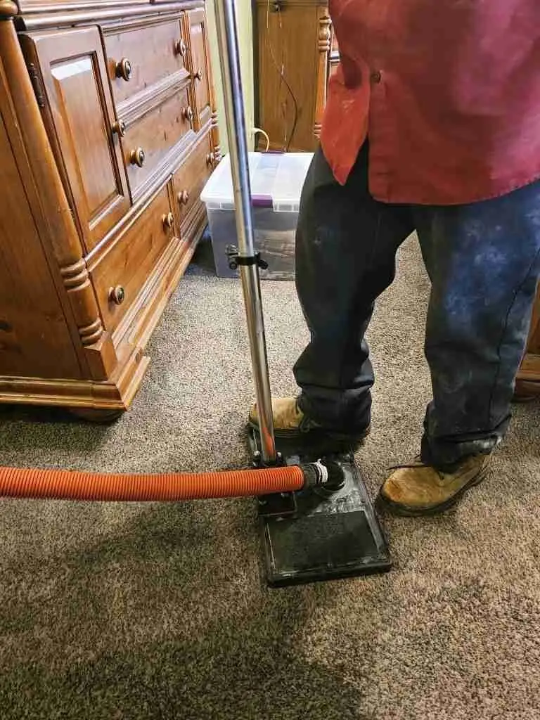 Technician using a water extraction tool on soaked carpet