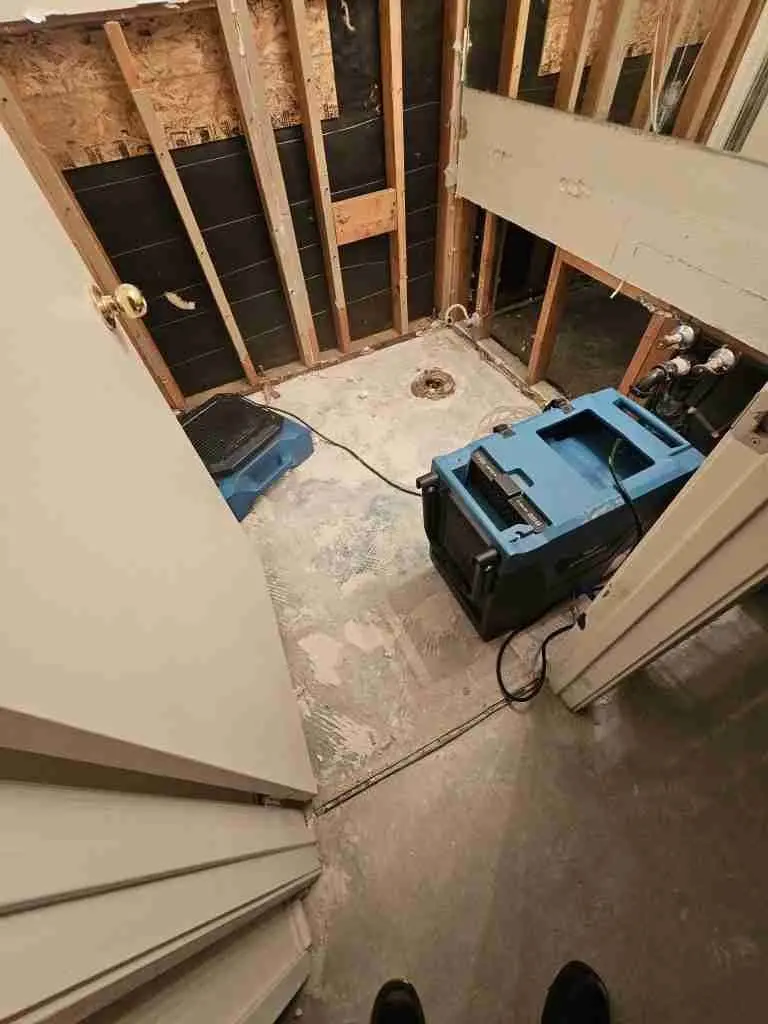 Utility area with drywall removed and a dehumidifier drying the space after a leak
