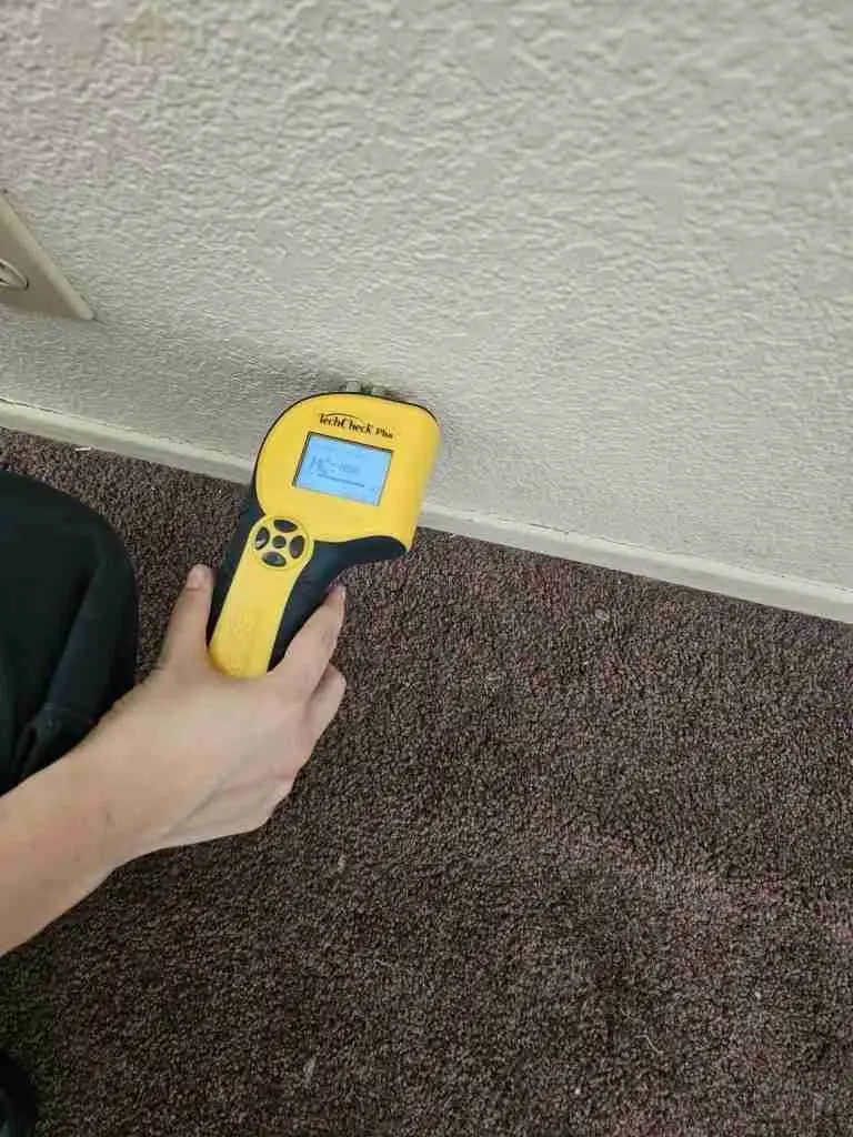 Rapid Response technician checking a wall with a moisture meter to trace a hidden leak