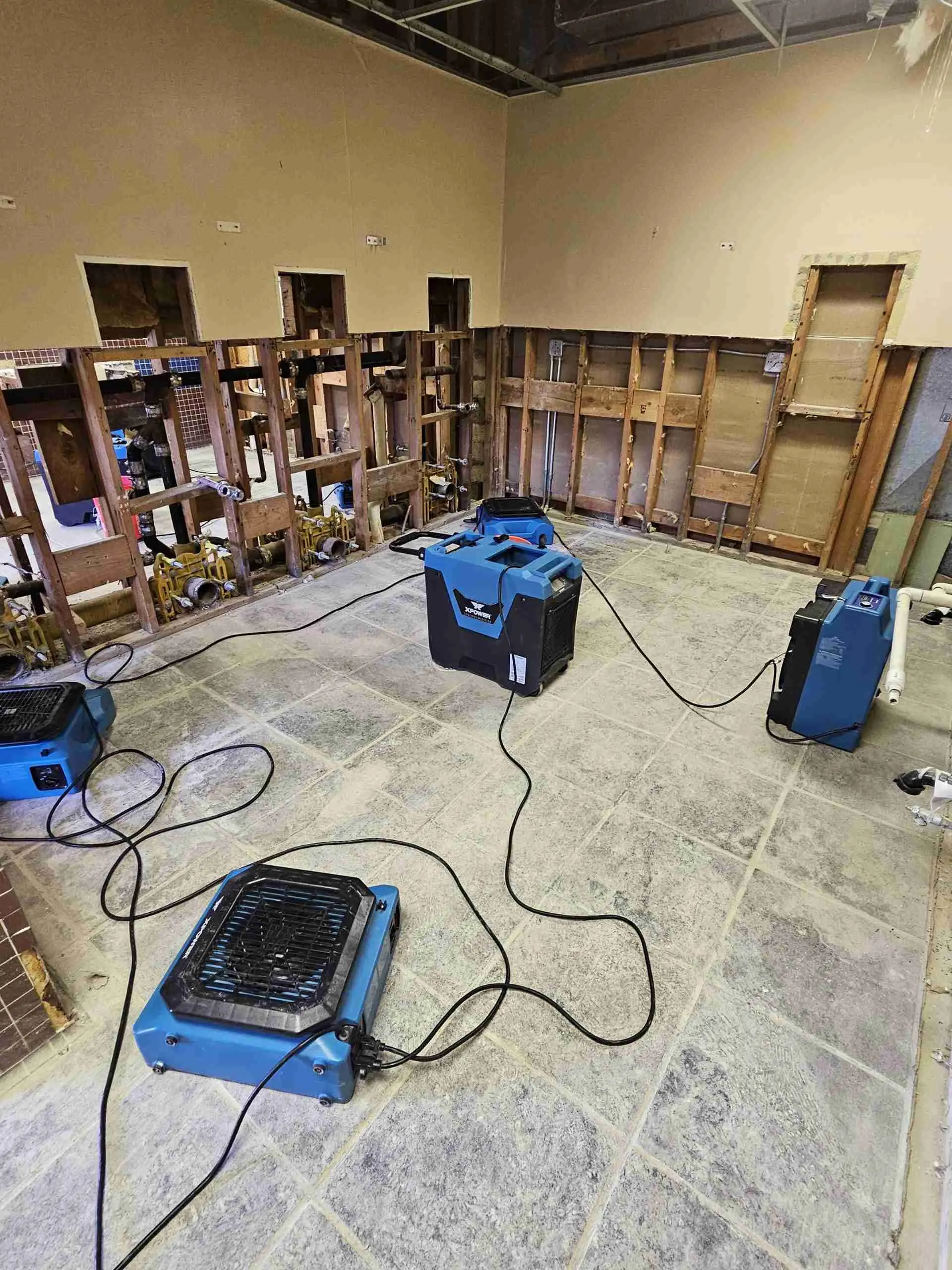 Room with drywall removed and air movers drying the framing after water damage on a Rapid Response job